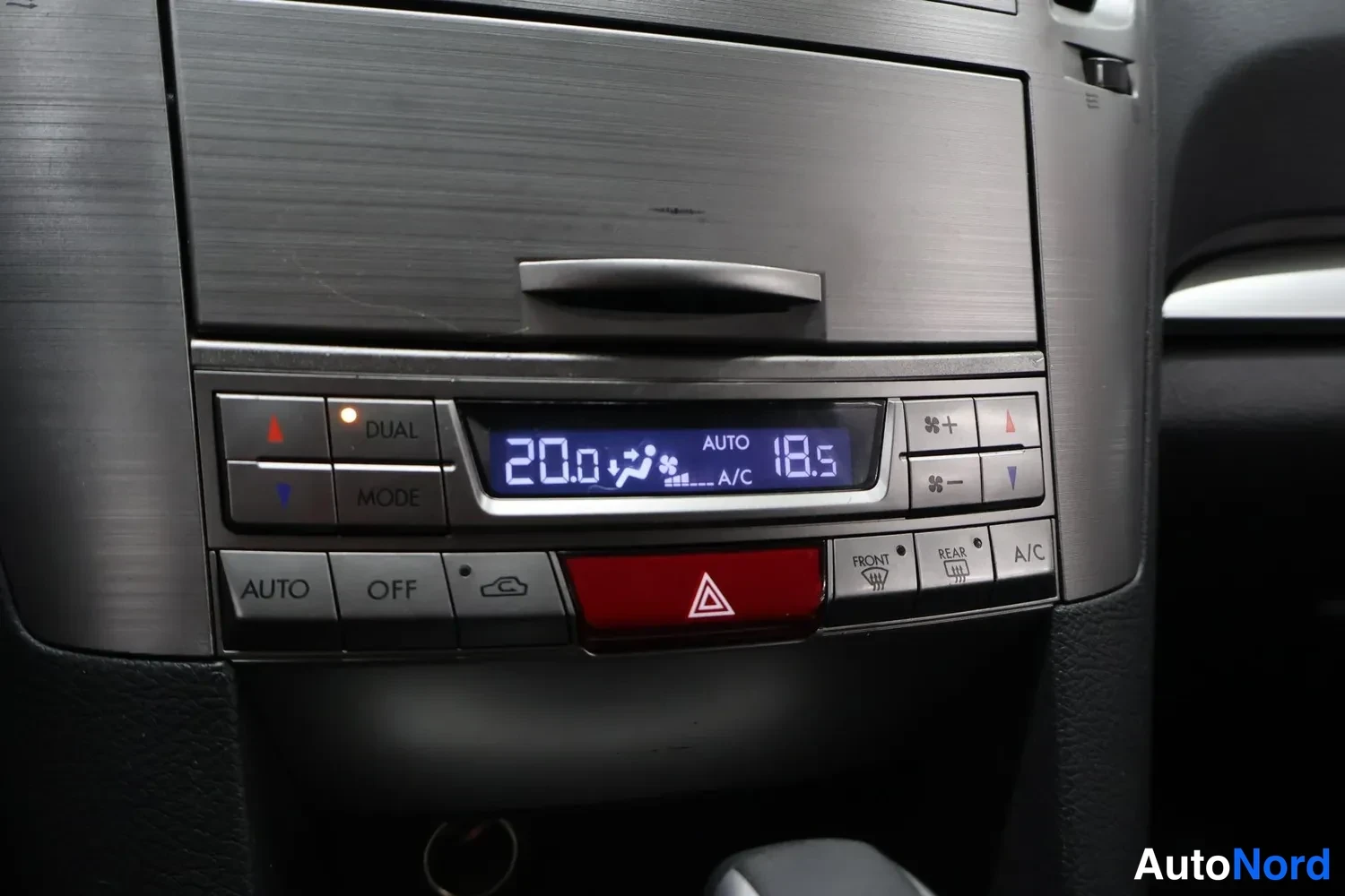 Muu: Lähikuva ilmastoinnin ohjauspaneelista: DUAL- ja MODE-nappi, näytöllä 20.0 ja 18.5 sekä AUTO ja A/C, alapuolella AUTO-, OFF-, FRONT- ja REAR-lämmitinnapit sekä