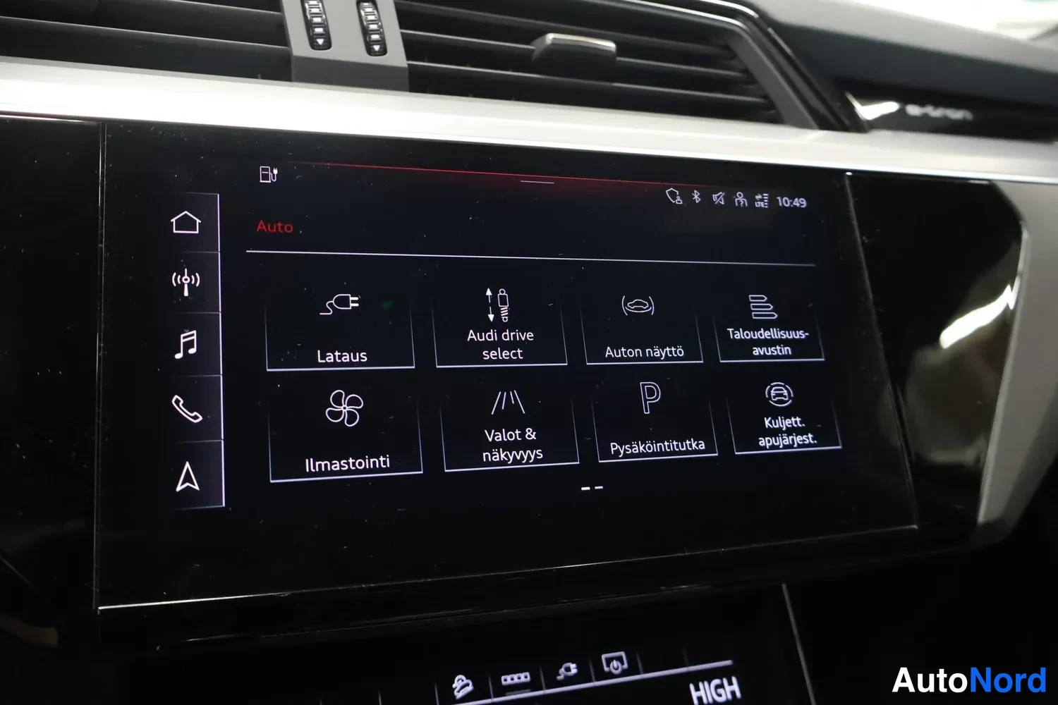Yksityiskohta: Audi e-tronin kojelaudan keskiosan kosketusnäyttö, jossa on valikko vaihtoehdoilla Lataus, Audi drive select, Auton näyttö, Taloudellisuusavustin, Ilmastointi,