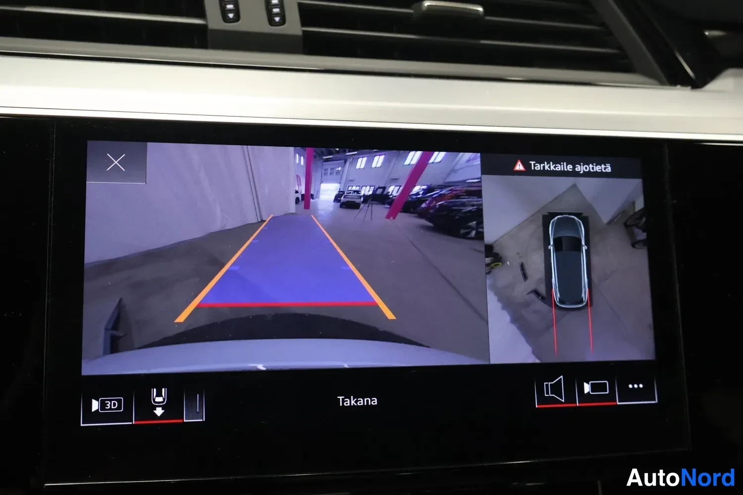 Yksityiskohta: Infotainment-näytöllä peruutuskameran kuva ja ajorataopas, tekstit Tarkkaile ajotietä ja Takana.