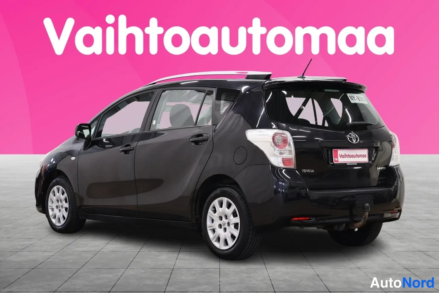 Takaviisto: Musta Toyota Verso -henkilöauto taka-ja sivunäkymässä, perä oikealla, takaosassa Toyota-merkki.
