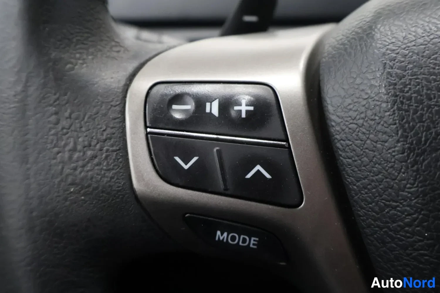 Yksityiskohta: Ratin Multi-STEERING-wheel-ohjaimet: äänenvoimakkuus-, MODE- ja nuolinäppäimet.