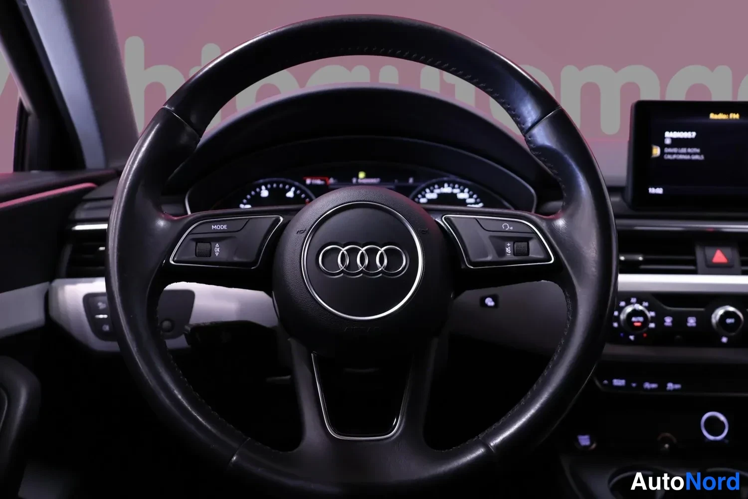 Muu: Ohjausteen ja kojelaudan näkymä: Audi-merkki ohjauspyörässä, mittaristo ja radio käynnissä.
