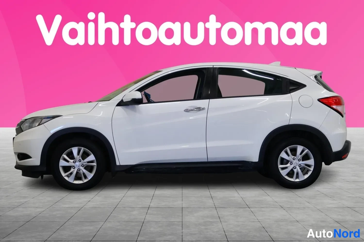 Etuviisto, nokka vasemmalle: Valkoinen Honda HR-V:n kylki ja keula vasemmasta etukulmasta, pinkki tausta.