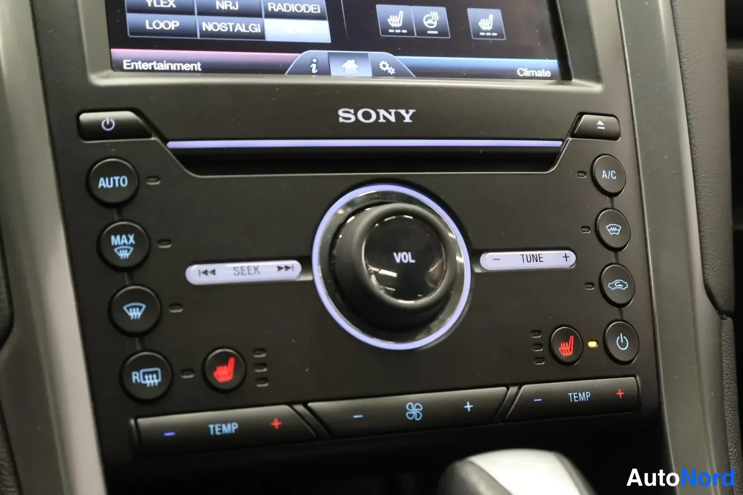 Yksityiskohta: Lämmitys- ja äänijärjestelmän ohjauspaneeli AUTO-, MAX-, A/C- ja TEMP-painikkeilla, VOL-säädimellä, teksti SONY sekä istutinlämmitys- ja Webasto-tyyppiset merkk