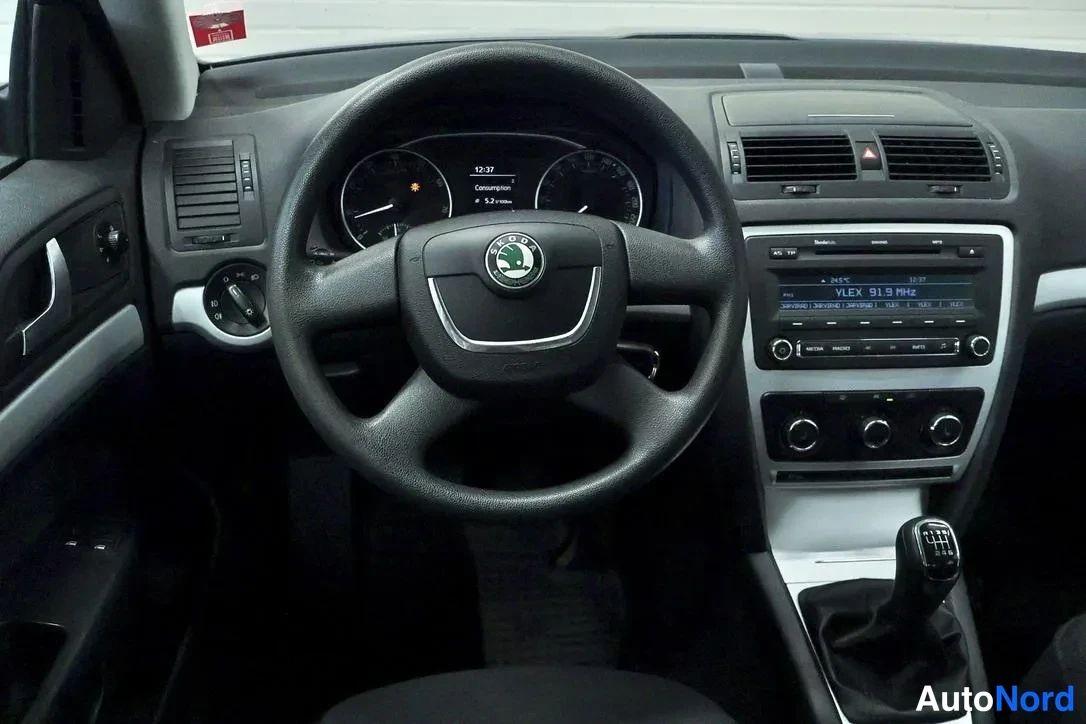 Muu: Autojen sisätilat: Skoda-ohjauspyörä, mittaristo ja radiopaneeli, manuaalivaihteiston vaihdekeppi keskikonsolissa.