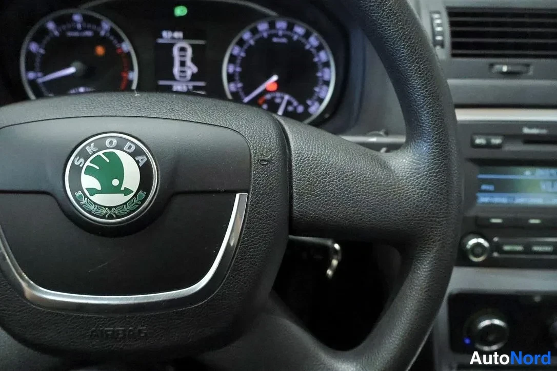 Muu: Lähikuva Skoda-ohjauspyörästä AIRBAG-merkinnällä; mittaristo ja osa radiopaneelista taustalla.