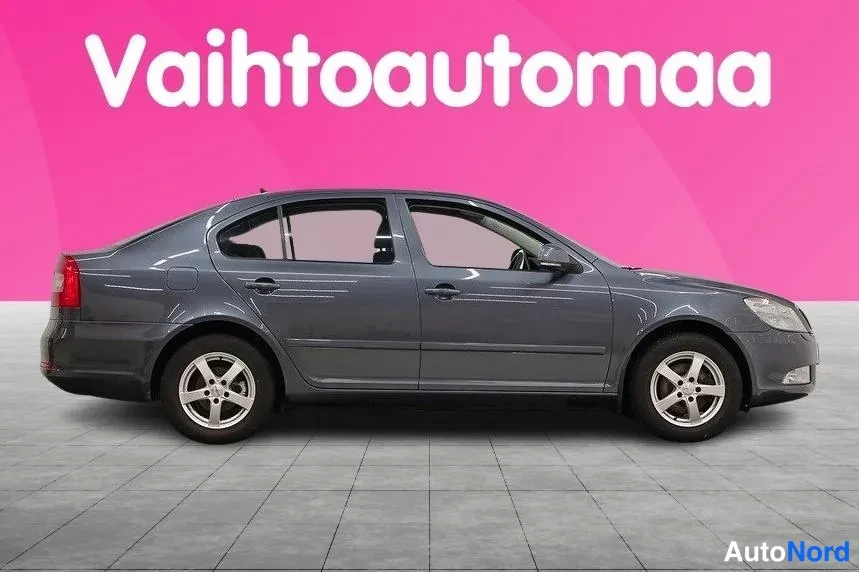 Sivulta: Profile view of the same grey car on a grey tiled floor against a pink background. Only the driver's side flank is visible; no front face or rear face is shown.