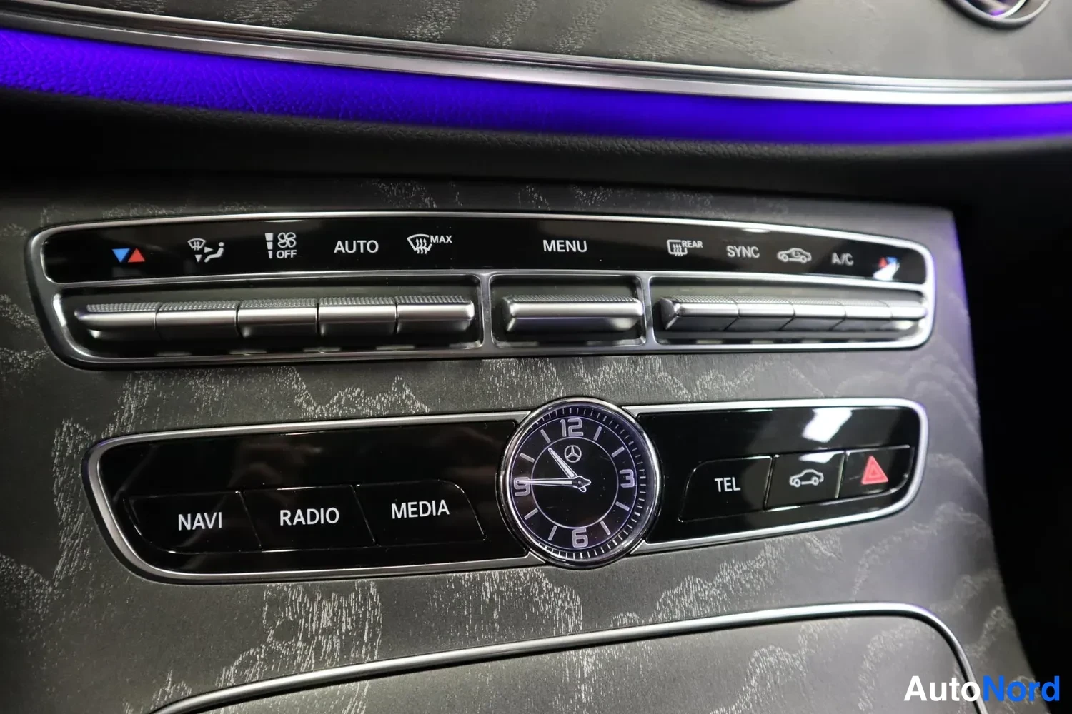 Yksityiskohta: Riistamon ilmastointi- ja medianäppäimet: AUTO, MENU, SYNC, A/C sekä NAVI, RADIO, MEDIA ja analoginen kello.