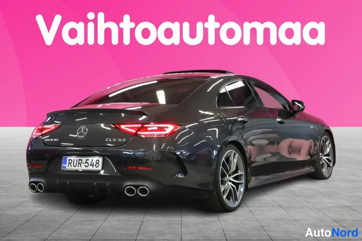 Takaviisto: Taka kolmasosakuva tummanharmaasta Mercedes-Benz AMG CLS 53 -coupesta; vasen kylki ja takapää näkyvissä, kiiltävät vanteet ja -kilpi.