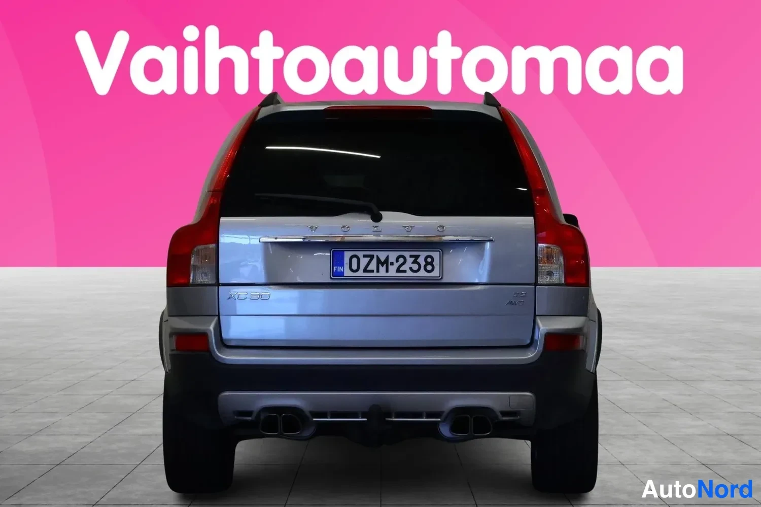 Takaa: Volvo XC90 suoraan takaa, rekisteritunnus, XC90-merkintä takaluukussa ja kaksiosaiset pakoputket näkyvissä.