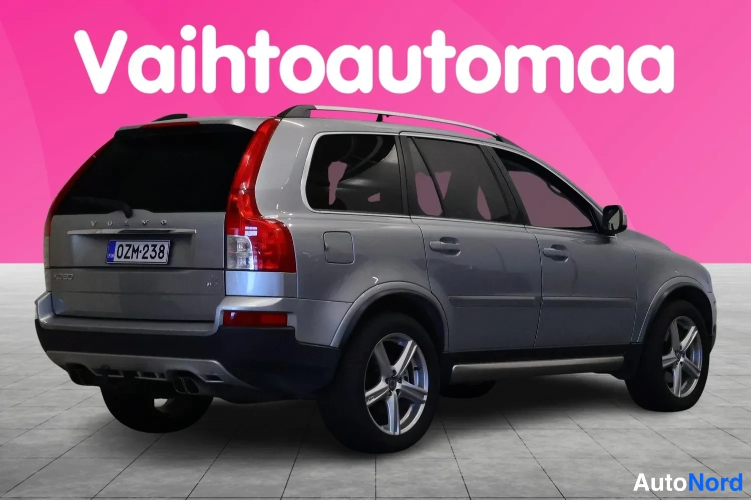 Takaviisto: Hopeanharmaa farmariliikenneauto takaviistosta, rekisterikilpi, kuvattu studiotaustaa vasten.