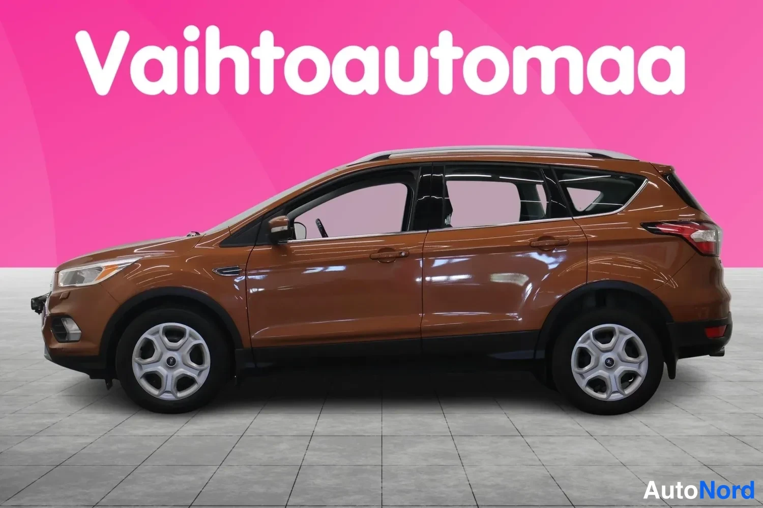 Etuviisto, nokka vasemmalle: Ruskea Ford Kuga -farmurin korinen SUV kuvattu etukulmasta vasemmalta, katuharjoitteluvalot ja hopeiset kevytmetallivanteet näkyvät.
