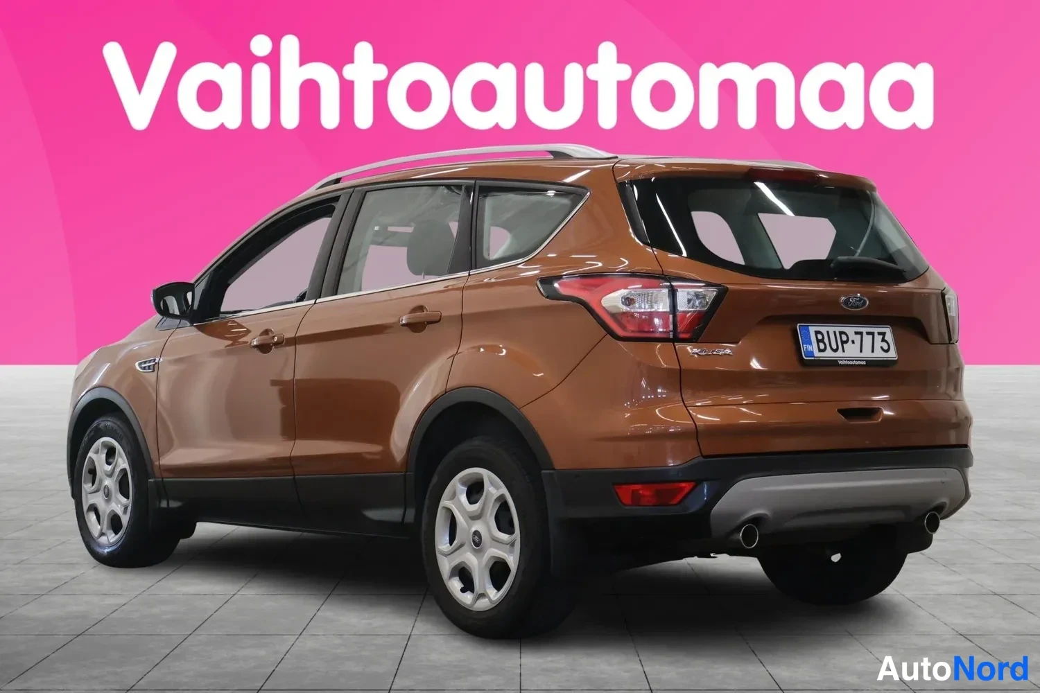 Takaviisto: Ruskea Ford Kuga kuvattu takakulmasta oikealta, rekisterikilpi ja hopeiset kevytmetallivanteet näkyvät.