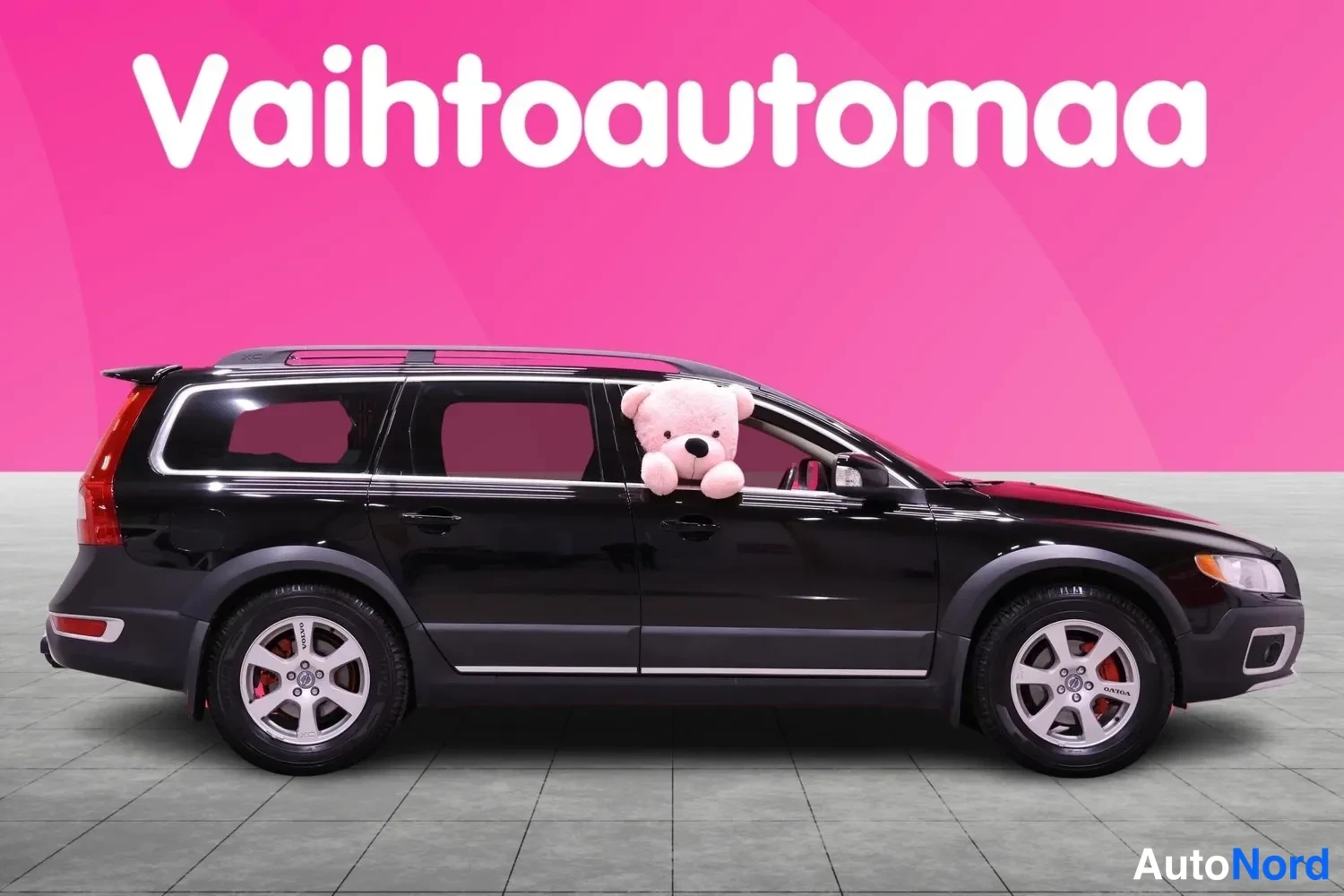 Sivulta: Vasemman puolen kyljen näkymä mustasta Volvo XC70:stä, takapenkiltä näkyvät penkit, takavalot ja kattopalkit