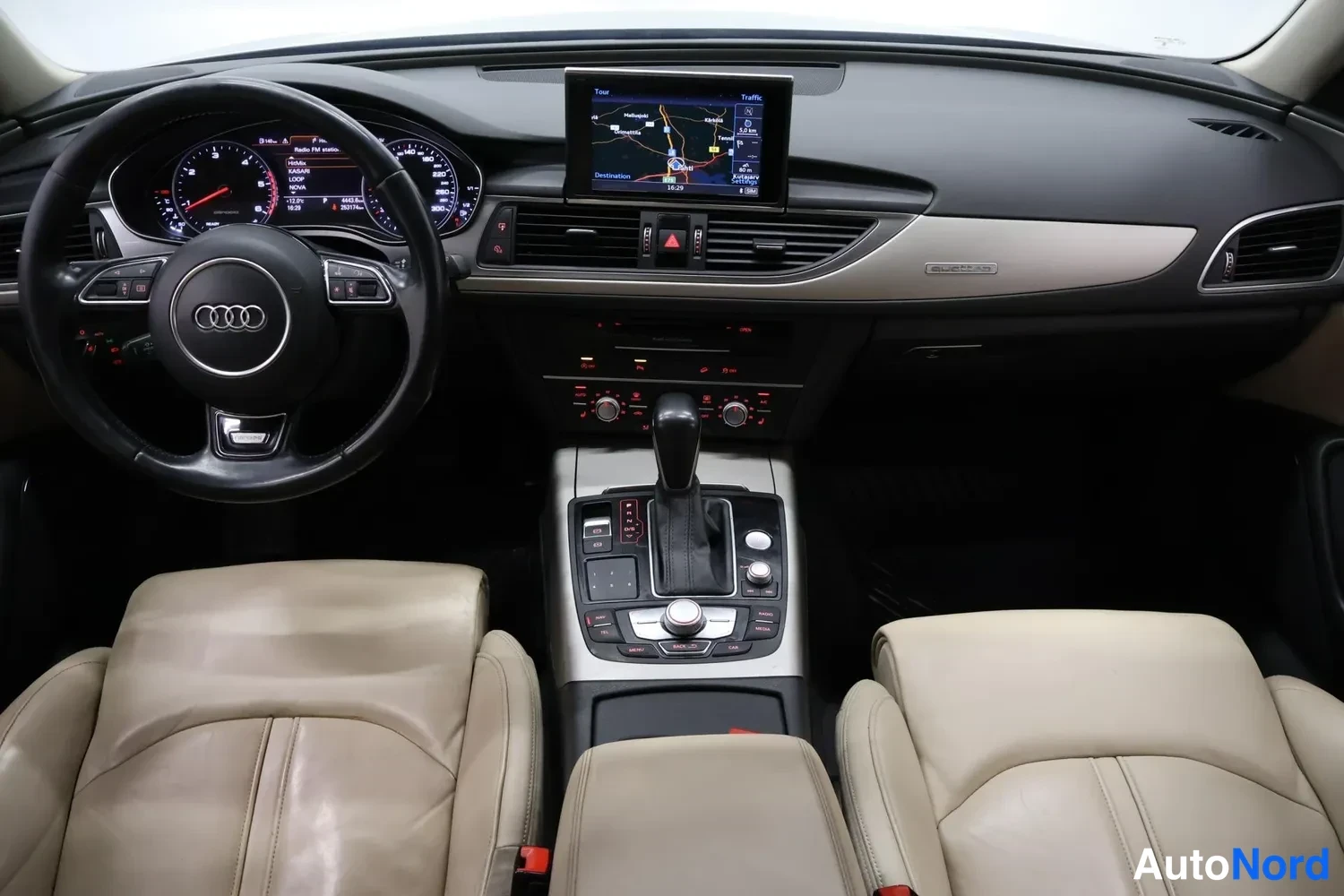 Yksityiskohta: Matkustamon yleiskuva etualalta: beige nahkapenkit, Audi-ohjauspyörä, MMI-navigaatio ja automaattivaihteen valitsin.