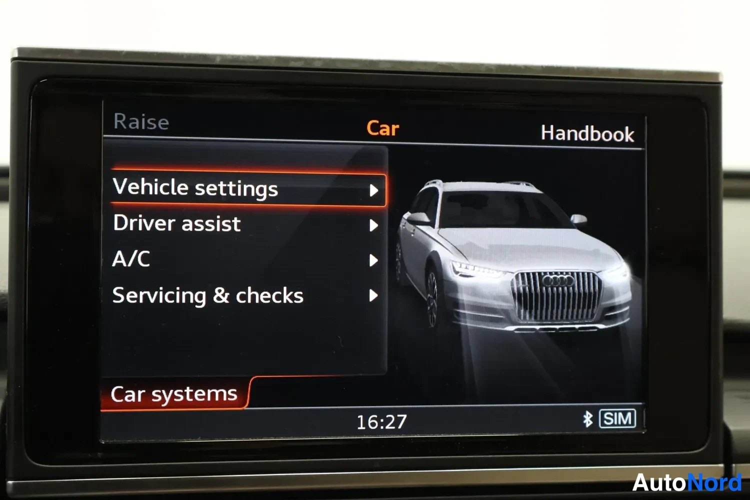 Yksityiskohta: Autoin päällä: MMI-näyttö, jossa Car-valikko kohdilla Vehicle settings, Driver assist, A/C ja Servicing & checks. Kellonaika 16:27.