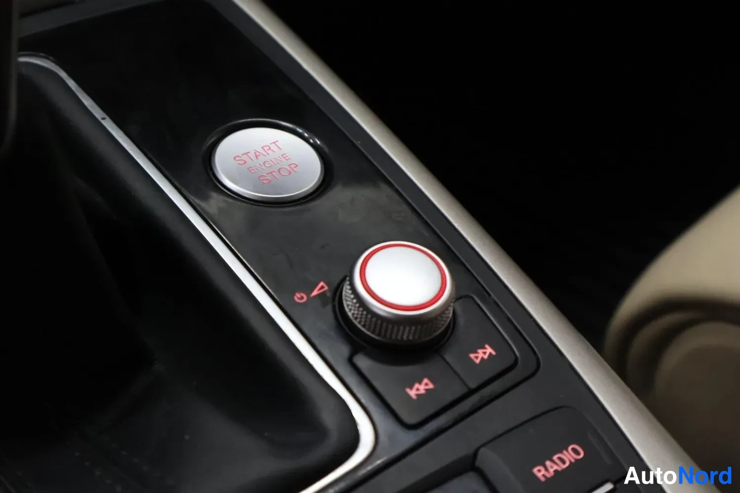 Yksityiskohta: START ENGINE STOP -käynnistysnappi ja multimediasäädin (RADIO) keskikonsolissa.