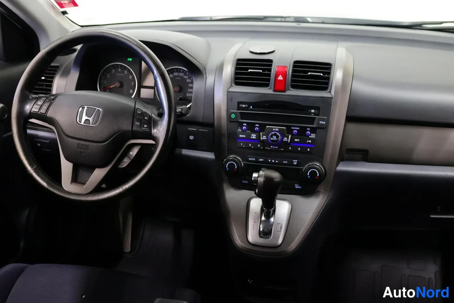 Muu: Honda CR-V:n kojelauta kuljettajan puolelta: Honda-ohjauspyörä, mittaristo, radio ja automaattivaihteiston valitsin.