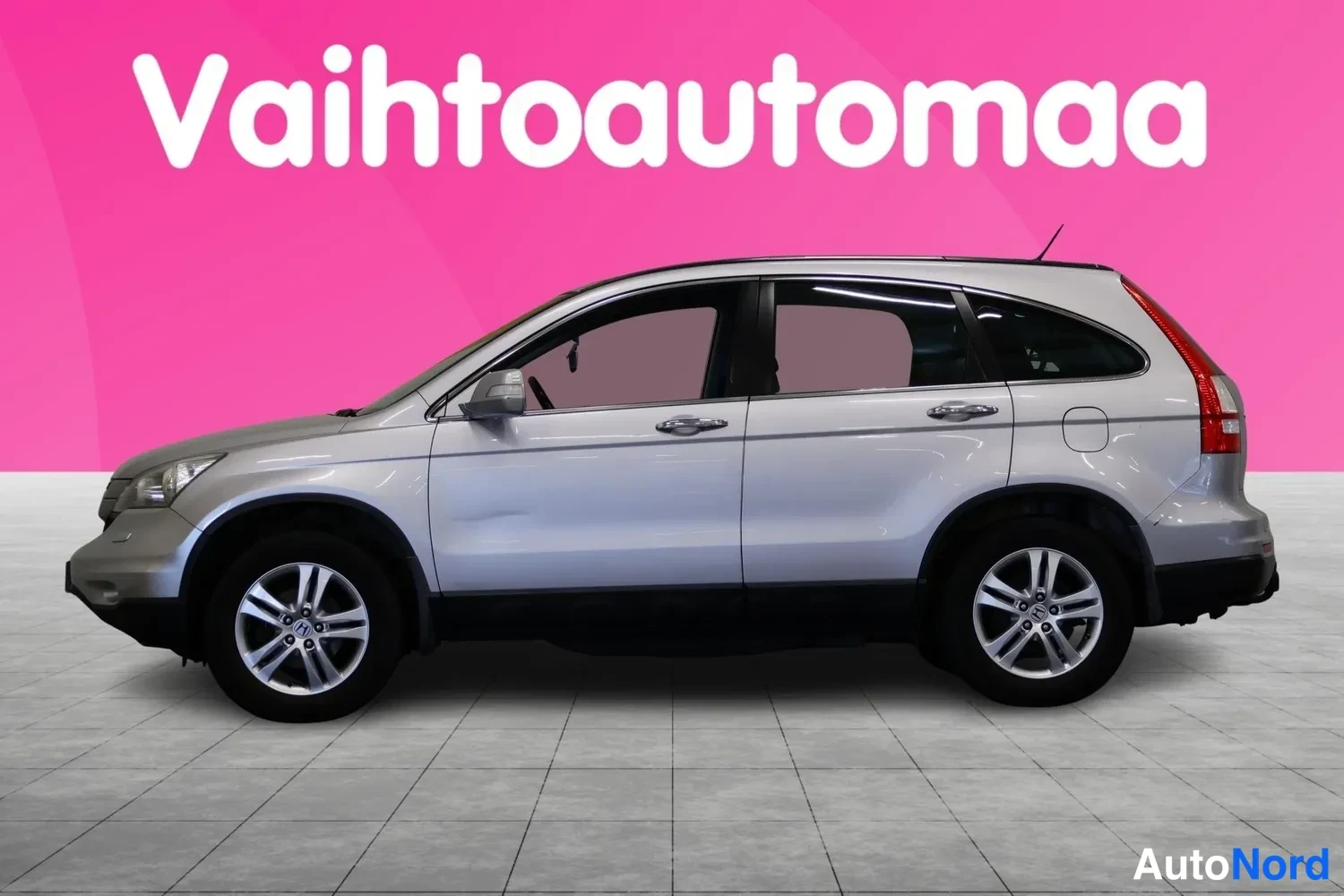 Sivulta: Hopeanharmaa Honda CR-V sivulta, kattoantenni ja hopeavanteet näkyvissä, pinkki tausta.