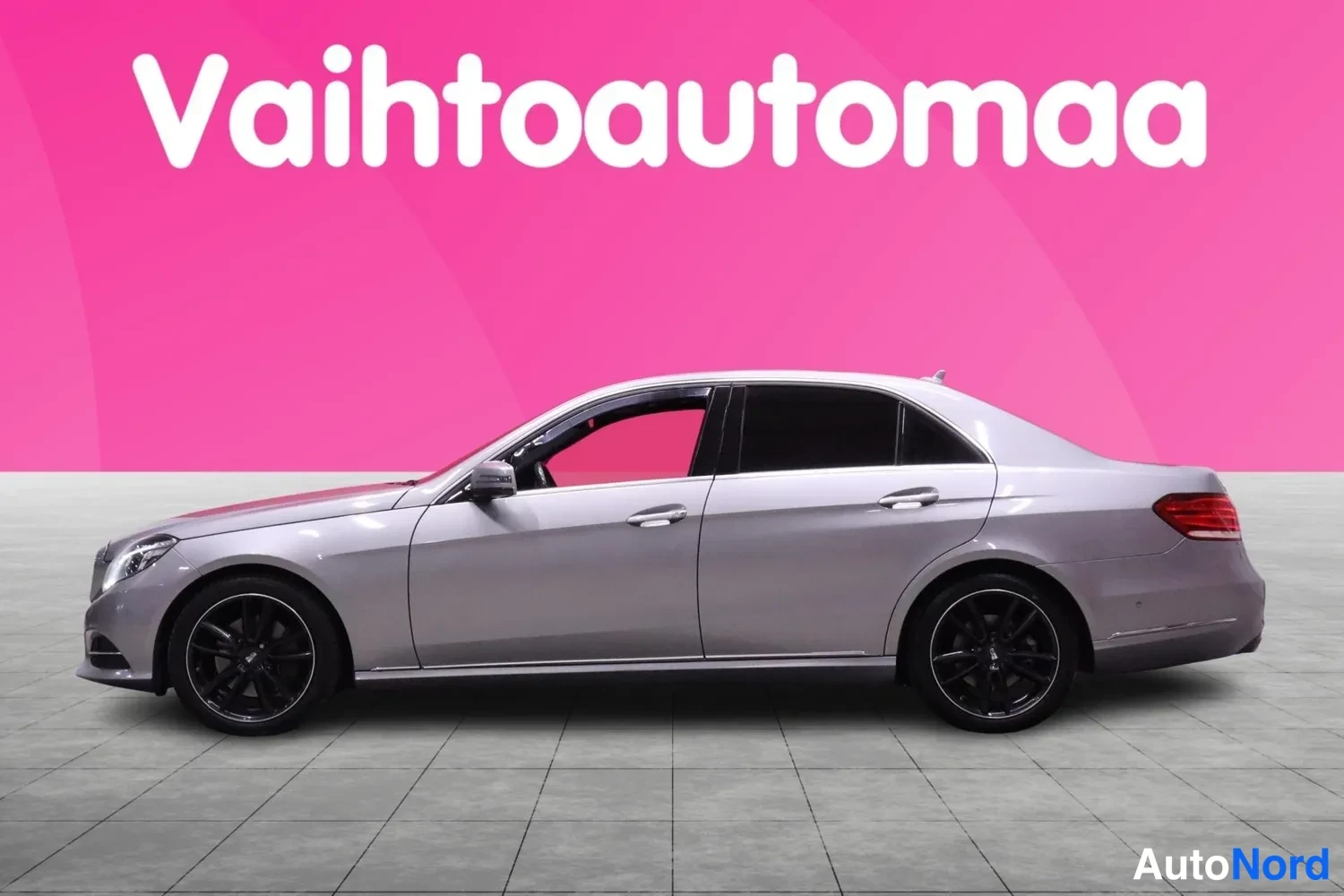 Etuviisto, nokka vasemmalle: Mercedes-Benz E-sarjan sedan sivulta vasemmasta suunnasta kuvattuna; hopeanvärinen kori, mustat kevytmetallivanteet.