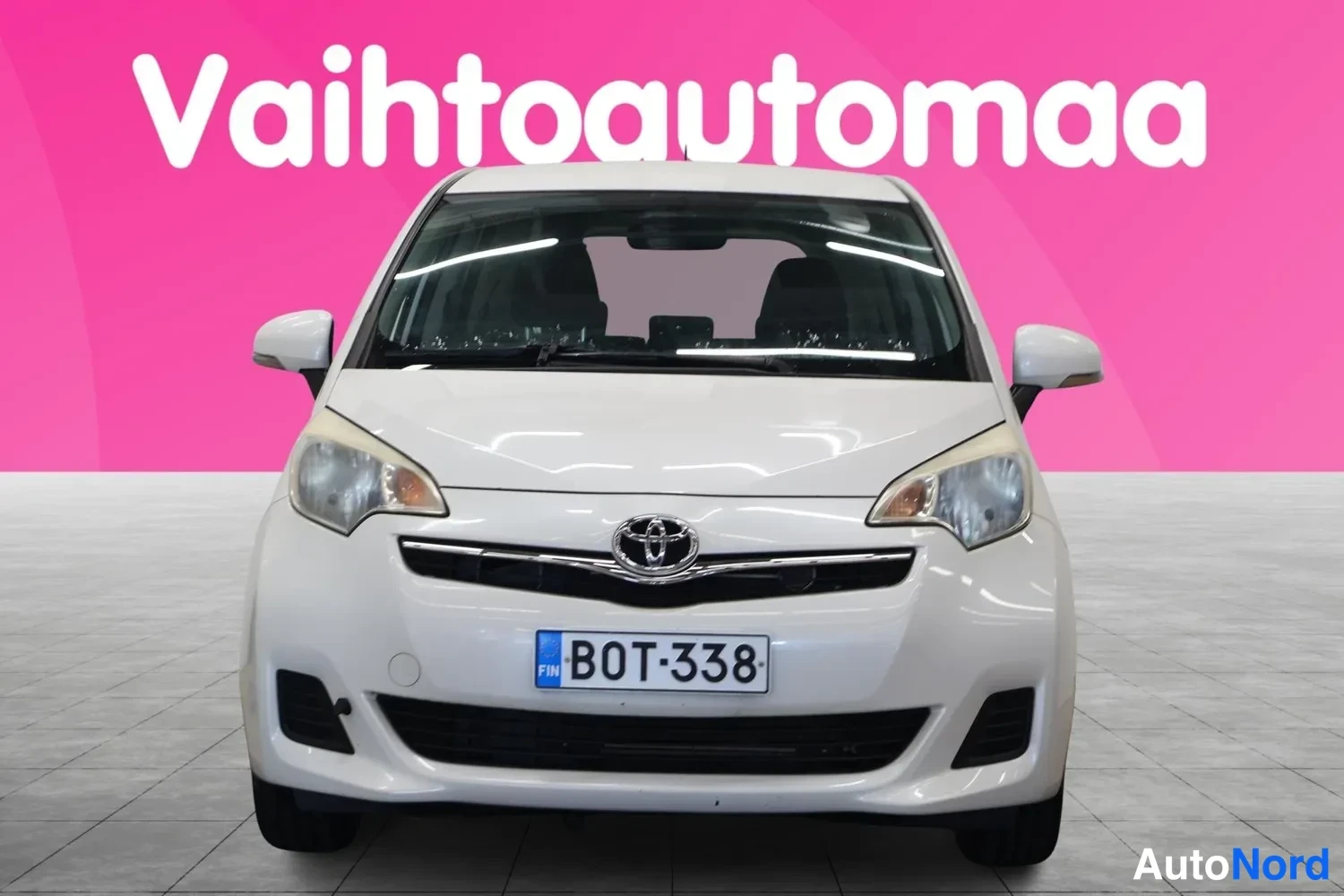 Edestä: Edestä kuvattu valkoinen auto, rekisterikilpi.