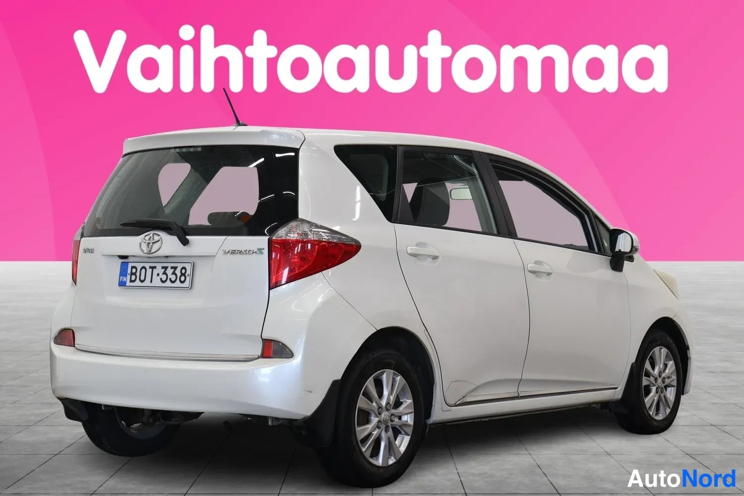 Takaviisto: Valkoinen Toyota Verso-S takaviistosta oikealta kuvattuna, rekisterikilpi.