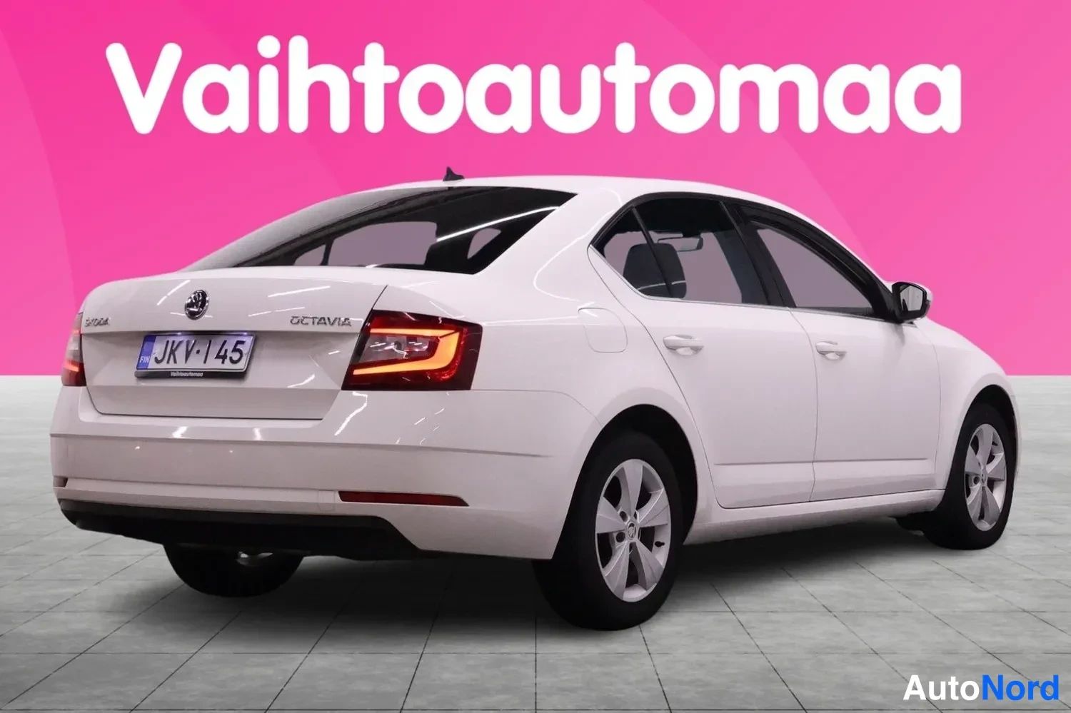 Takaviisto: Auton takaosan kolmasosakuva: valkoinen sedan, takavalo, -rekisterikilpi ja OCTAVIA-teksti näkyvät.