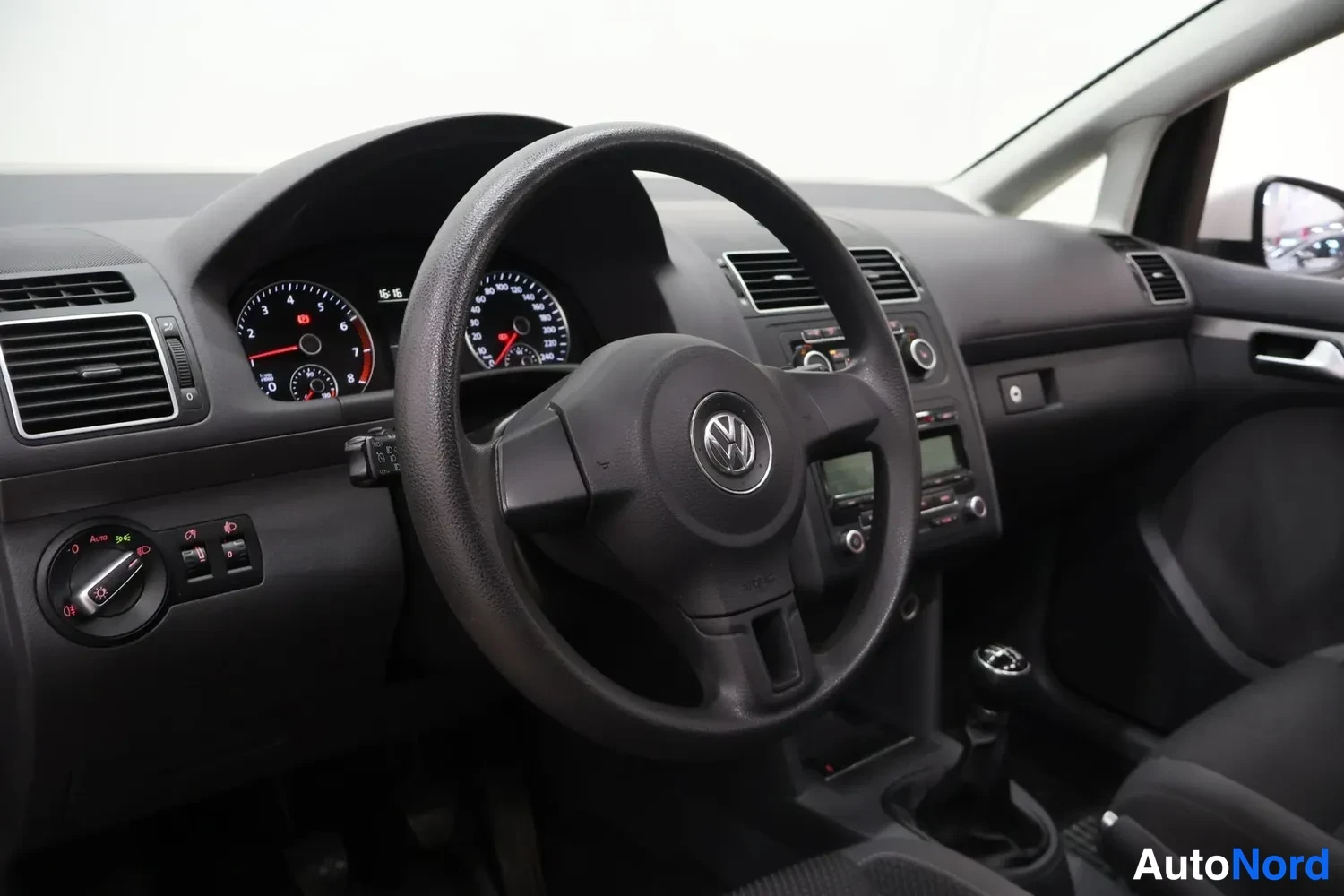 Muu: Ohjaamosta kuvattu näkymä: VW-merkillinen ohjauspyörä, mittaristo ja manuaalivaihteiston vaihdekeppi.