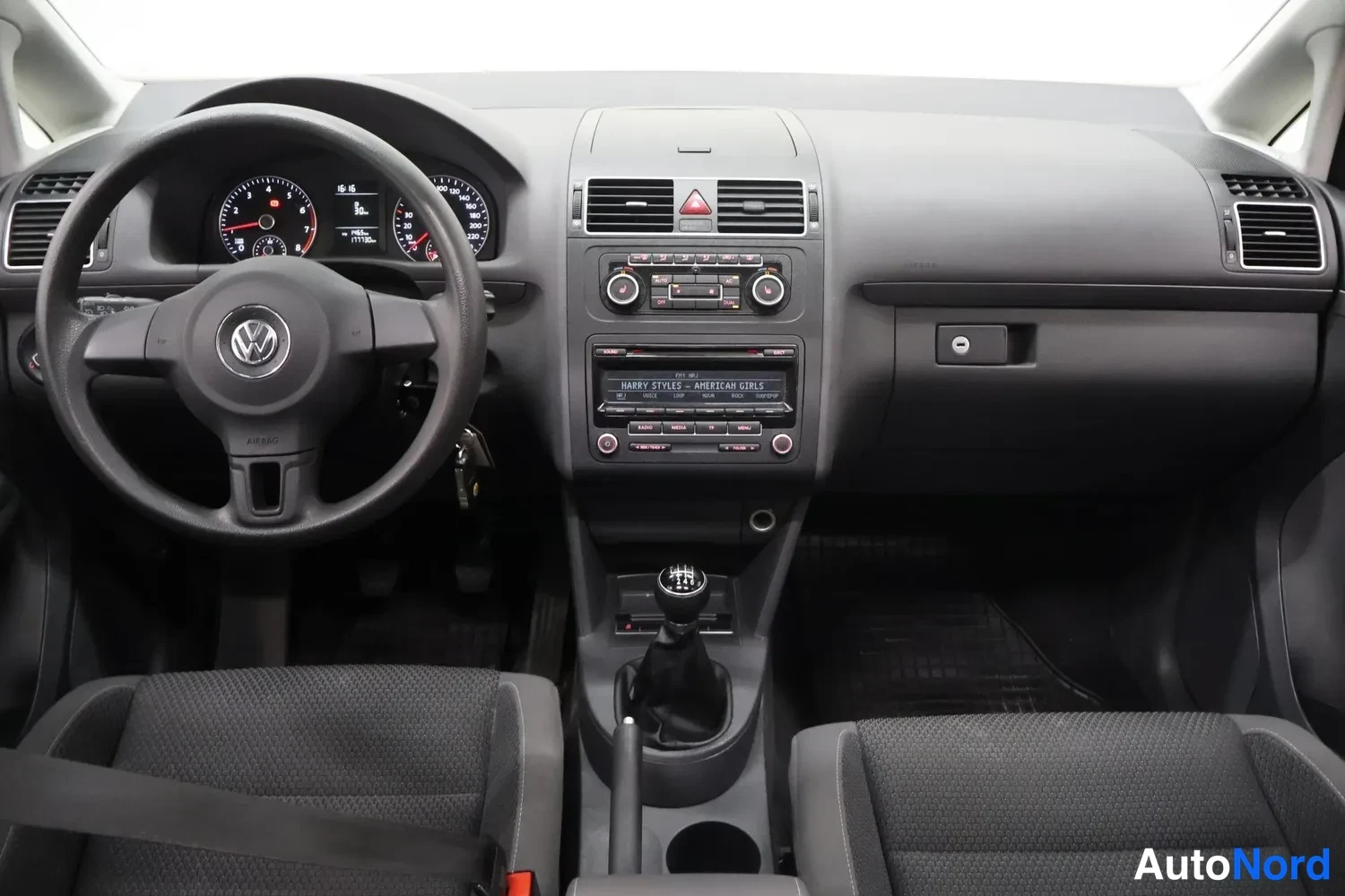 Yksityiskohta: Volkswagenin hallinta ohjaamosta: ratin takana analogiset mittarit, keskellä radio- ja ilmastointilaitteet, manuaalivaihtohetkin ja kaksi kangasistuinta