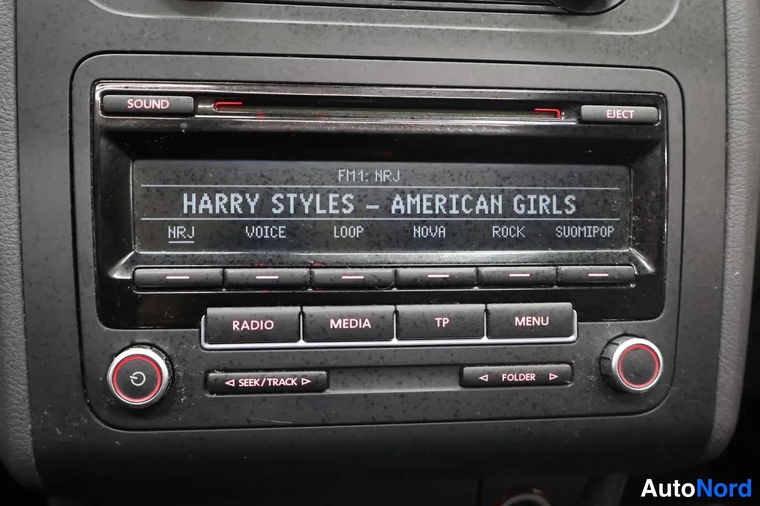 Yksityiskohta: Radiolinjan näyttö, jossa lukee FM1: NRJ ja HARRY STYLES – AMERICAN GIRLS, sekä RADIO-, MEDIA-, TP- ja MENU-painikkeet.