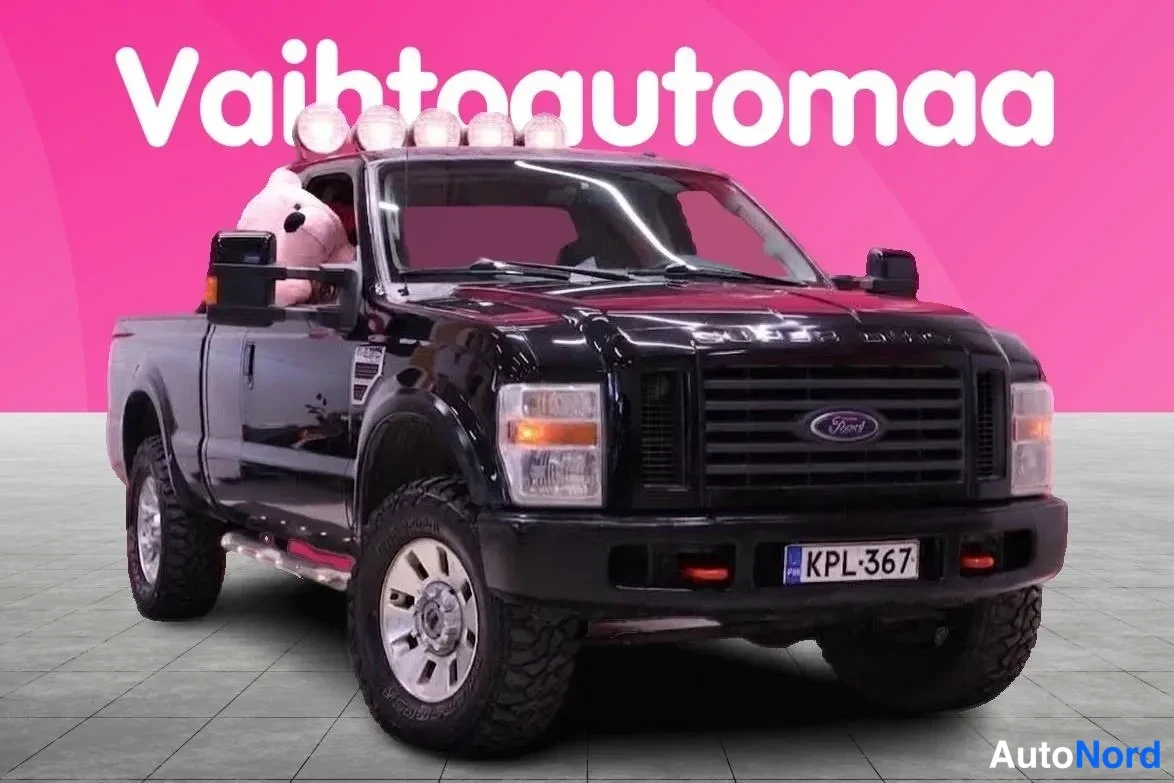 Etuviisto, nokka oikealle: Musta Ford Super Duty -kuorma-auto etukulmakuvassa, keula kuvan oikealla puolella. Katossa on viisivaloinen lisävaloake, etupuskurissa rekisterikilpi ja