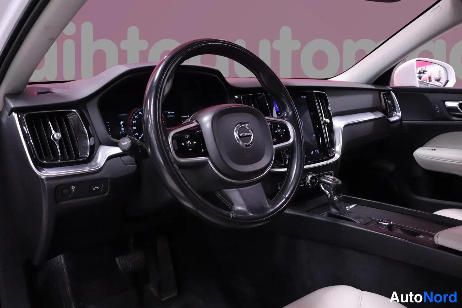 Muu: Volvo-merkkisen auton ohjaamo: musta ohjauspyörä, mittaristo ja keskikonsoli näkyvät kuljettajan puolelta kuvattuna.