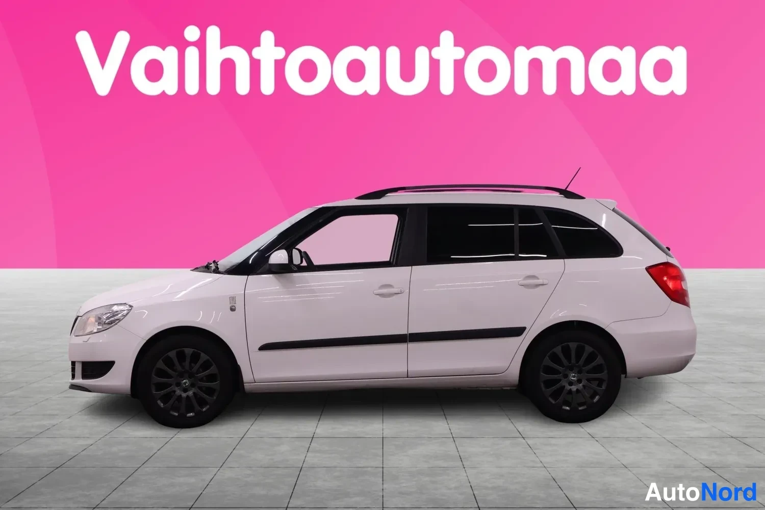 Sivulta: Skoda Fabia Combi sivusta vasemmalta valkoisena, kattokaiteet ja tummat pyöränkehät näkyvissä.