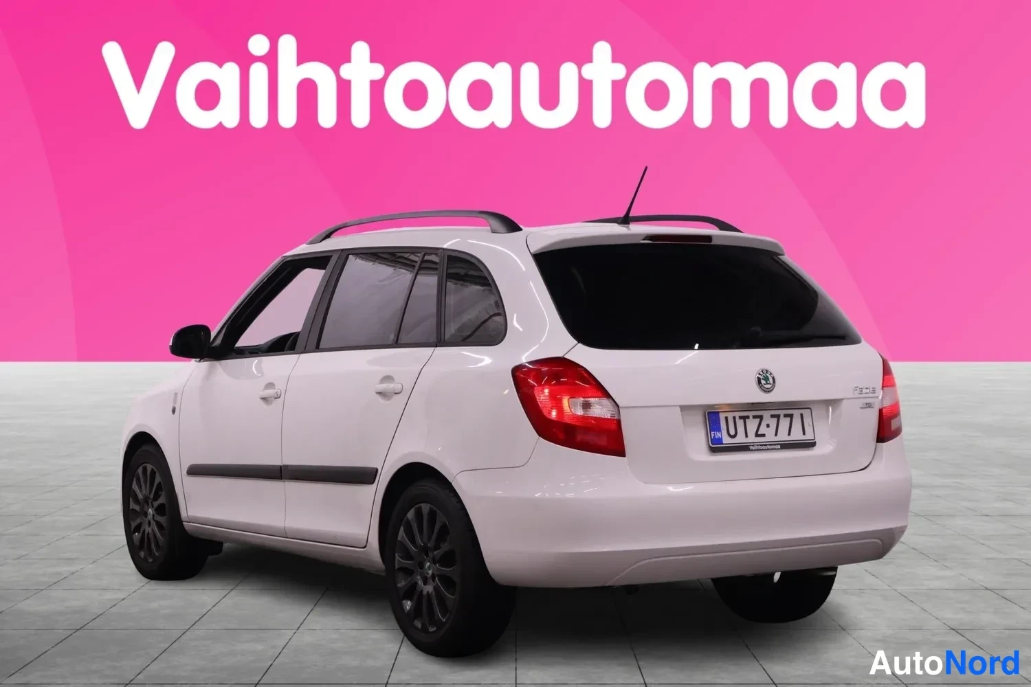 Takaviisto: Skoda Fabia Combi takaviistosta oikealta valkoisena, rekisteritunnus, kattokaiteet ja tummat pyöränkehät näkyvissä.