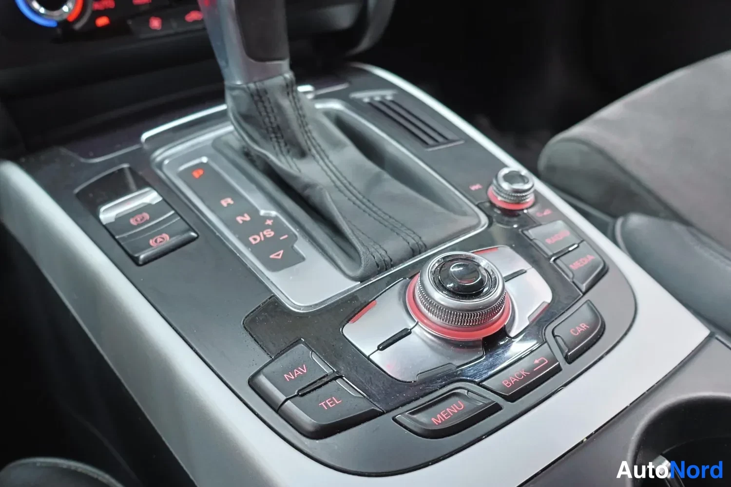 Muu: Keskikonsolin lähikuva: automaattivaihteen valitsin (P, R, N, D/S), pyörivä MMI-ohjain sekä NAV-, TEL-, MENU-, BACK-, CAR-, RADIO- ja MEDIA-painikkeet.