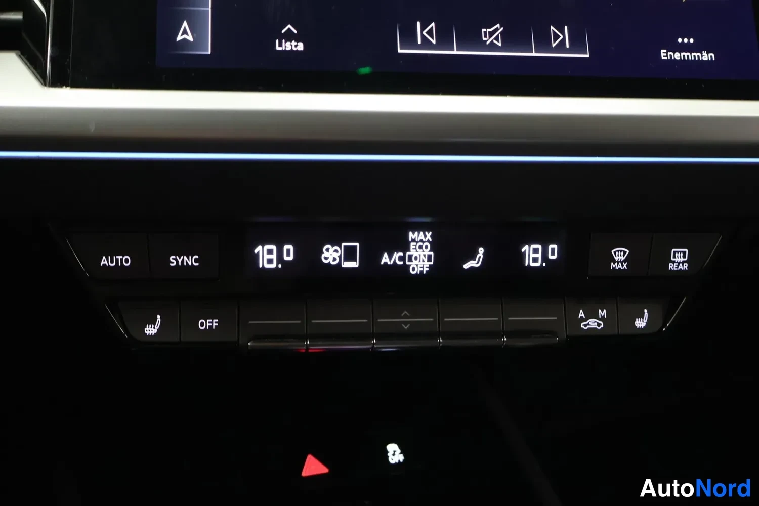 Muu: Ilmastointilaitteen säädinpöytä: AUTO, SYNC, molemmat lämpötilat 18.0 astetta, A/C, istuimenlämmitys ja MAX/REAR-merkkivalot.
