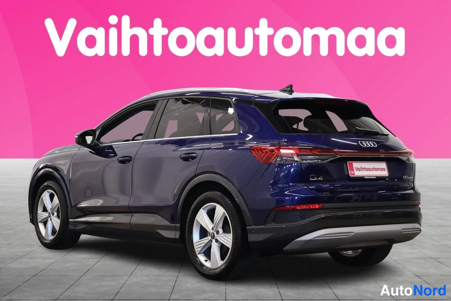 Takaviisto: Tummansininen Audi kulmataglauksesta takaa vasemmalta, perä ja vasen kylki näkyvissä; takaluukussa Q4-merkintä.