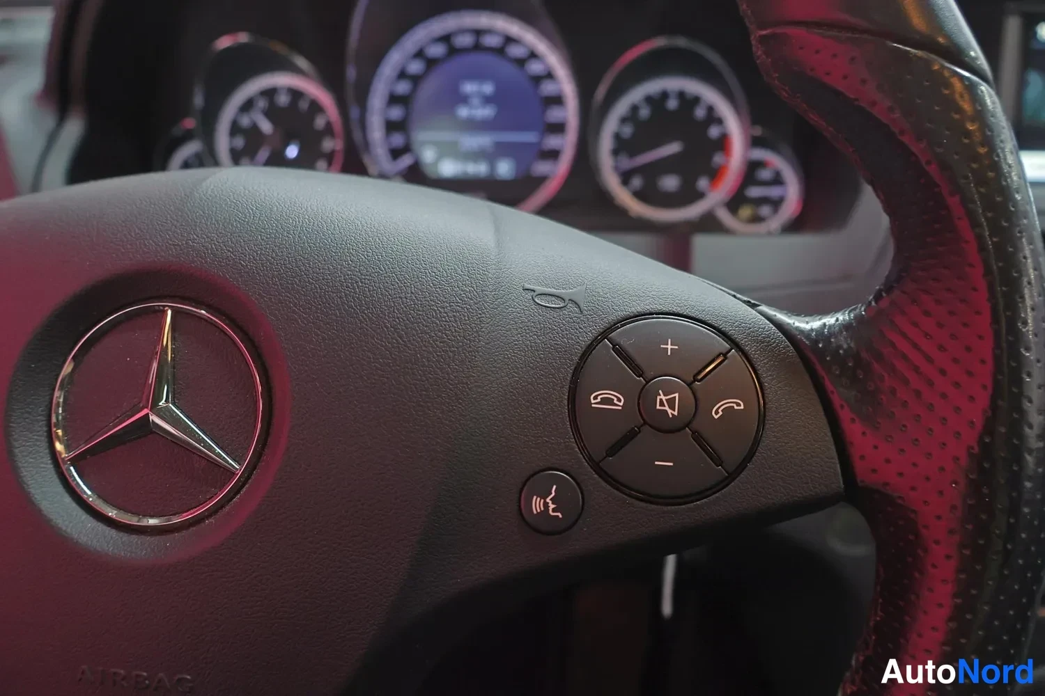 Muu: Ohjauspyörän keskiosa Mercedes-tähtimerkillä ja ääniohjaus- sekä puhelinpainikkeilla, taustalla mittaristo.