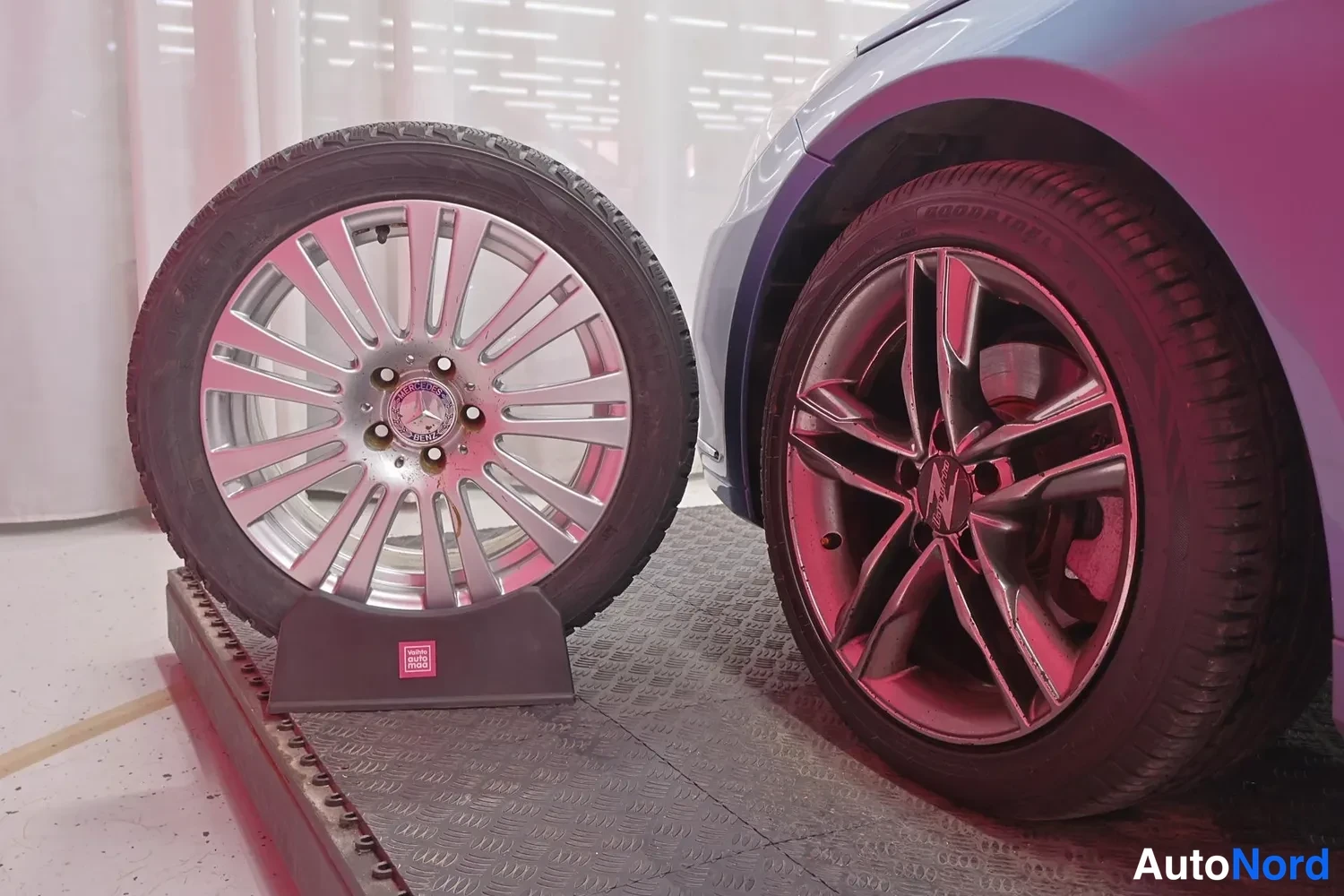 Muu: Kaksi rengasta rinnakkain: hopeinen monipuikkovannes Mercedes-merkinnällä ja autoon asennettu tumma moniosainen vannes Goodyear-renkaalla.