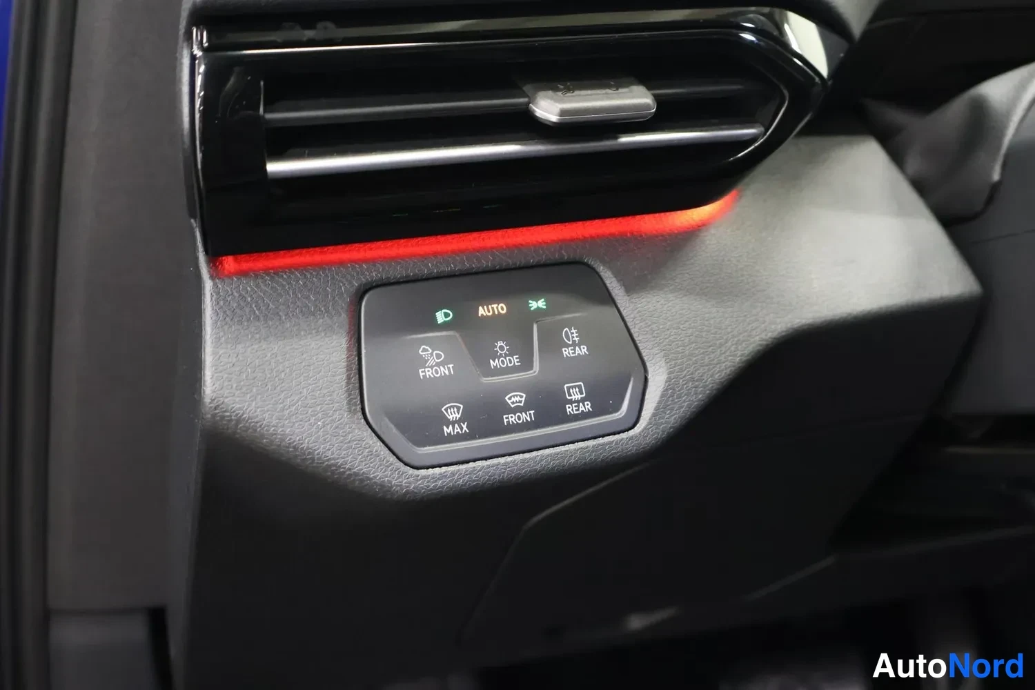 Muu: Kojeiston ilmastointipaneeli AUTO-, FRONT-, REAR-, MAX- ja MODE-merkeillä, yläpuolella ilmanvaihtoaukko ja punainen korostusvalo.