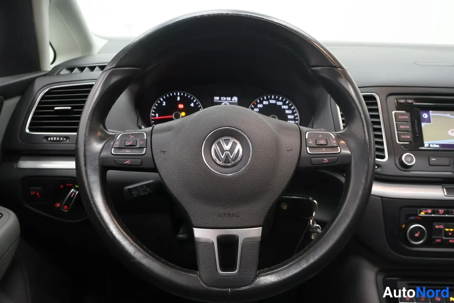Muu: Lähikuva Volkswagenin mustasta VW-ohjauspyörästä ja mittaristosta, AIRBAG-merkintä ohjauspyörän keskiössä.