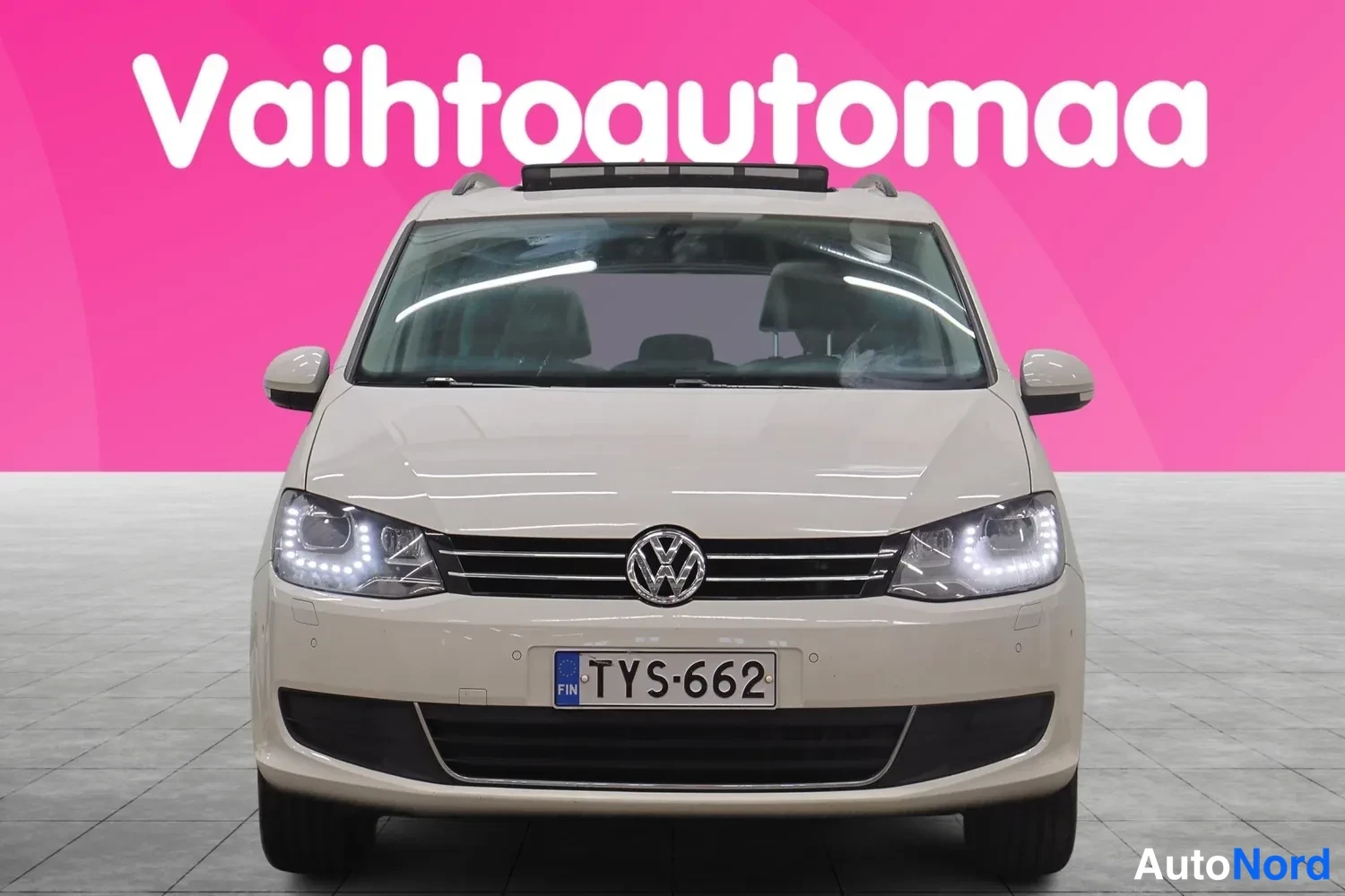 Edestä: Volkswagen Sharan edestäpäin, LED-päiväajovalot päällä, rekisteritunnus, panoraamakaton lasiluukku katolla.