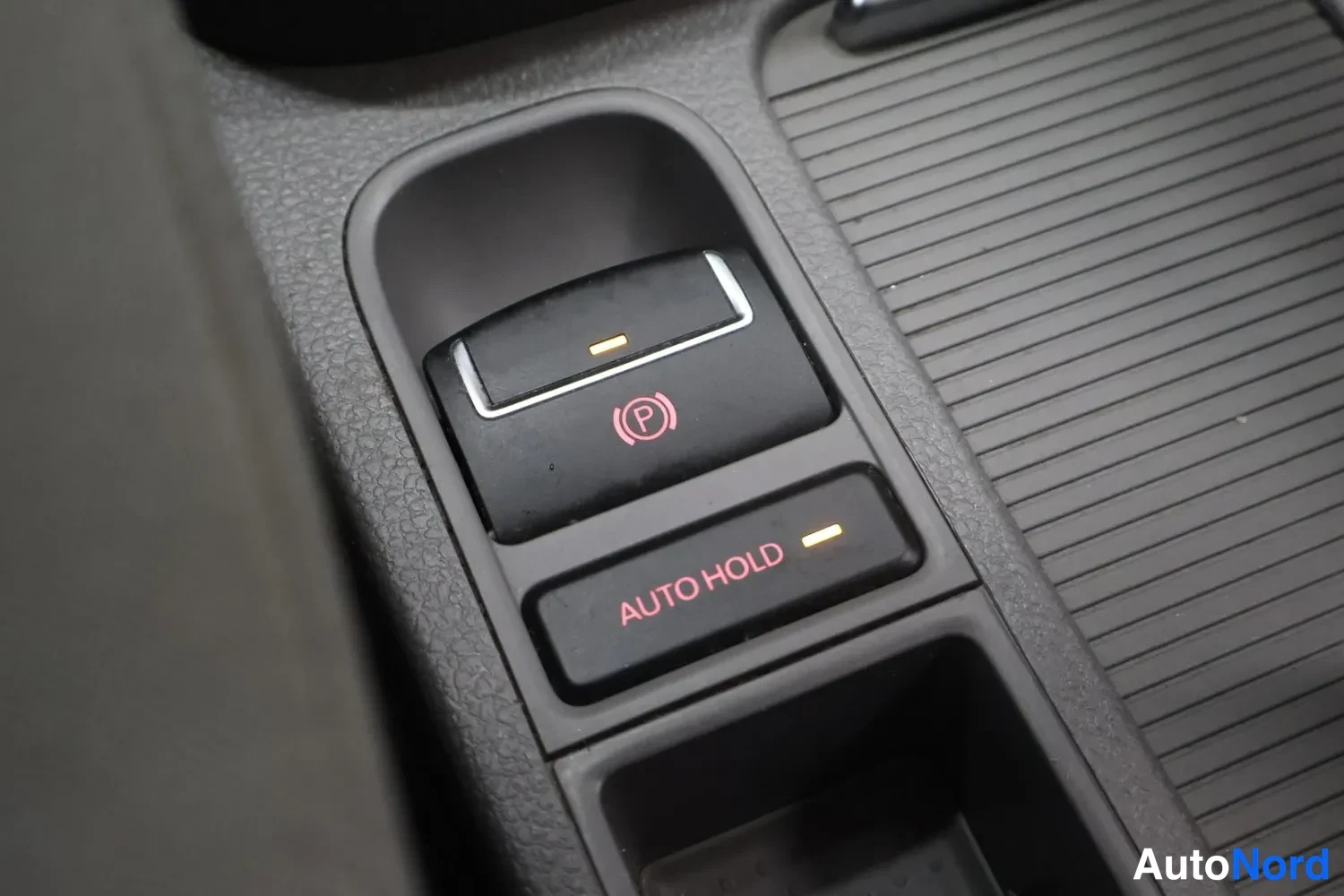 Muu: Keskiökkosella käsijarrupainike ja AUTO HOLD -painike, molemmat oranssilla valolla merkittyinä.