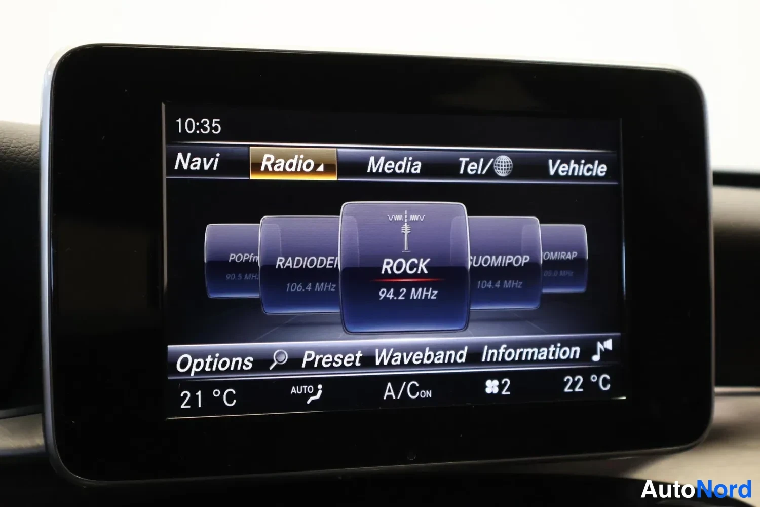 Muu: Keskirivin infotainment-näyttö radiokäyttöliittymässä: valittu kanava ROCK 94.2 MHz, alempana ilmastoinnin asetukset 21 °C ja 22 °C.