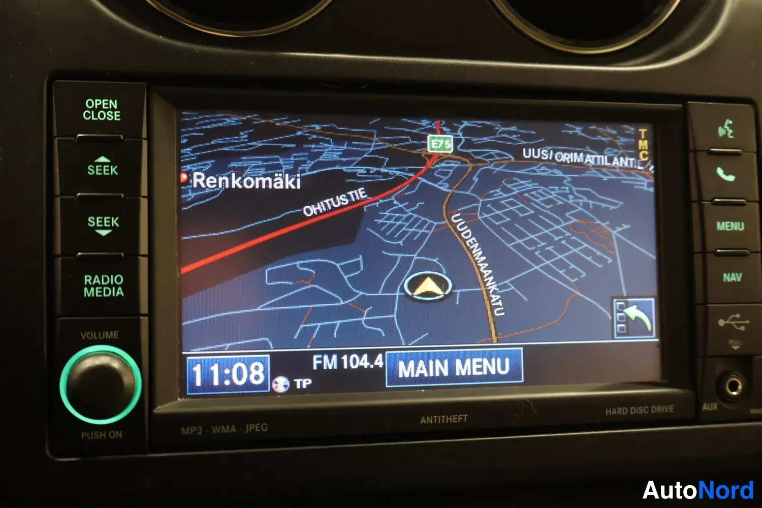 Yksityiskohta: Auton kojelautaan integroitu navigaatio- ja mediapaineenäyttö näyttää kartan ja FM 104.4 -radiokanavan.