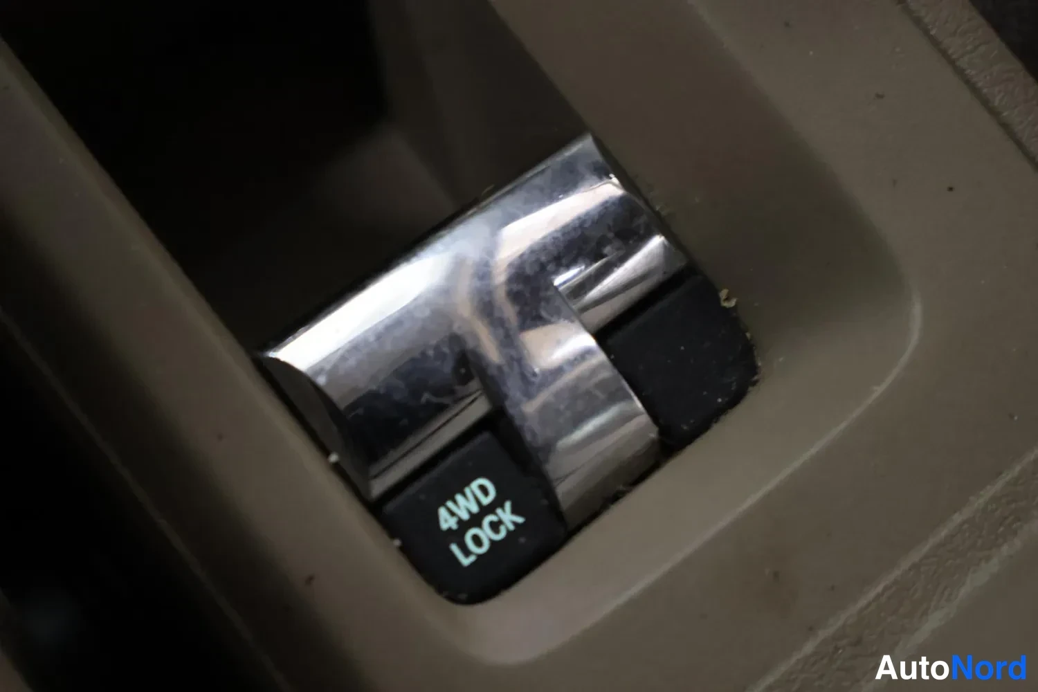 Yksityiskohta: Sisätilakuvan yksityiskohta: keskikonsolin kytkin, jossa lukee 4WD LOCK.