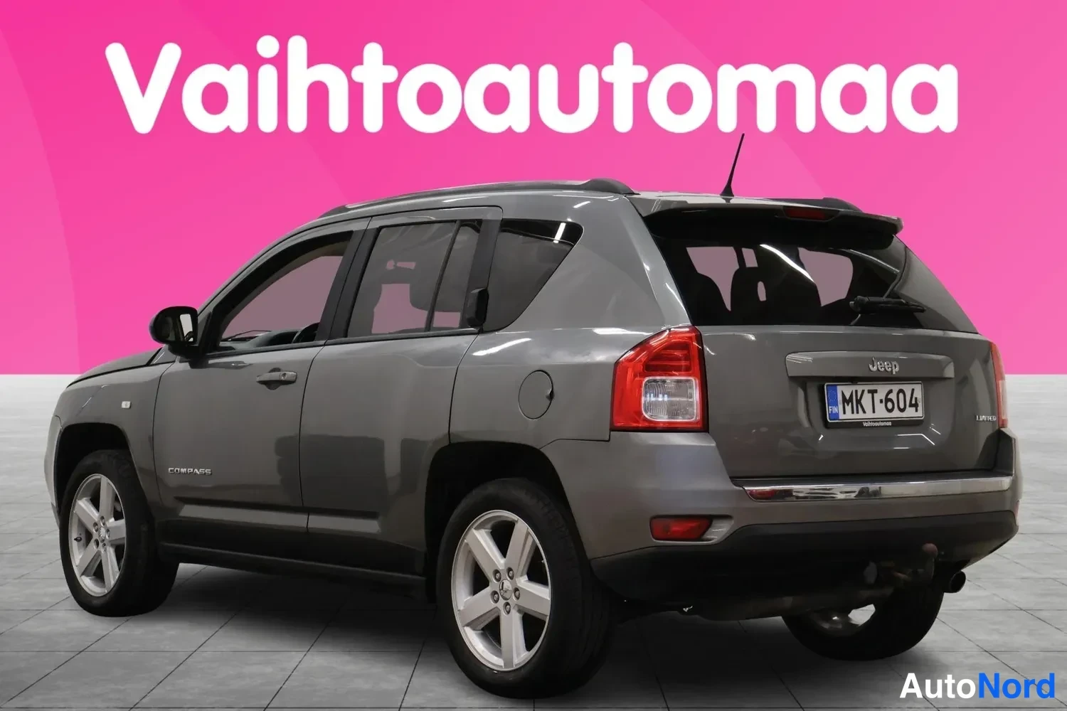Takaviisto: Auton taka­kulma vasemmalta, tummanharmaa Jeep Compass, rekisterikilpi.