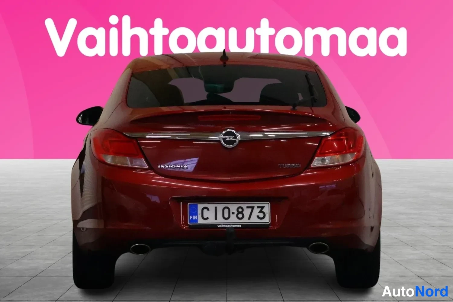 Takaa: Punaisen Opel Insignia -henkilöauton takaosa suoraan takaa, rekisterikilpi C10-873, kannessa tekstit INSIGNIA ja TURBO.