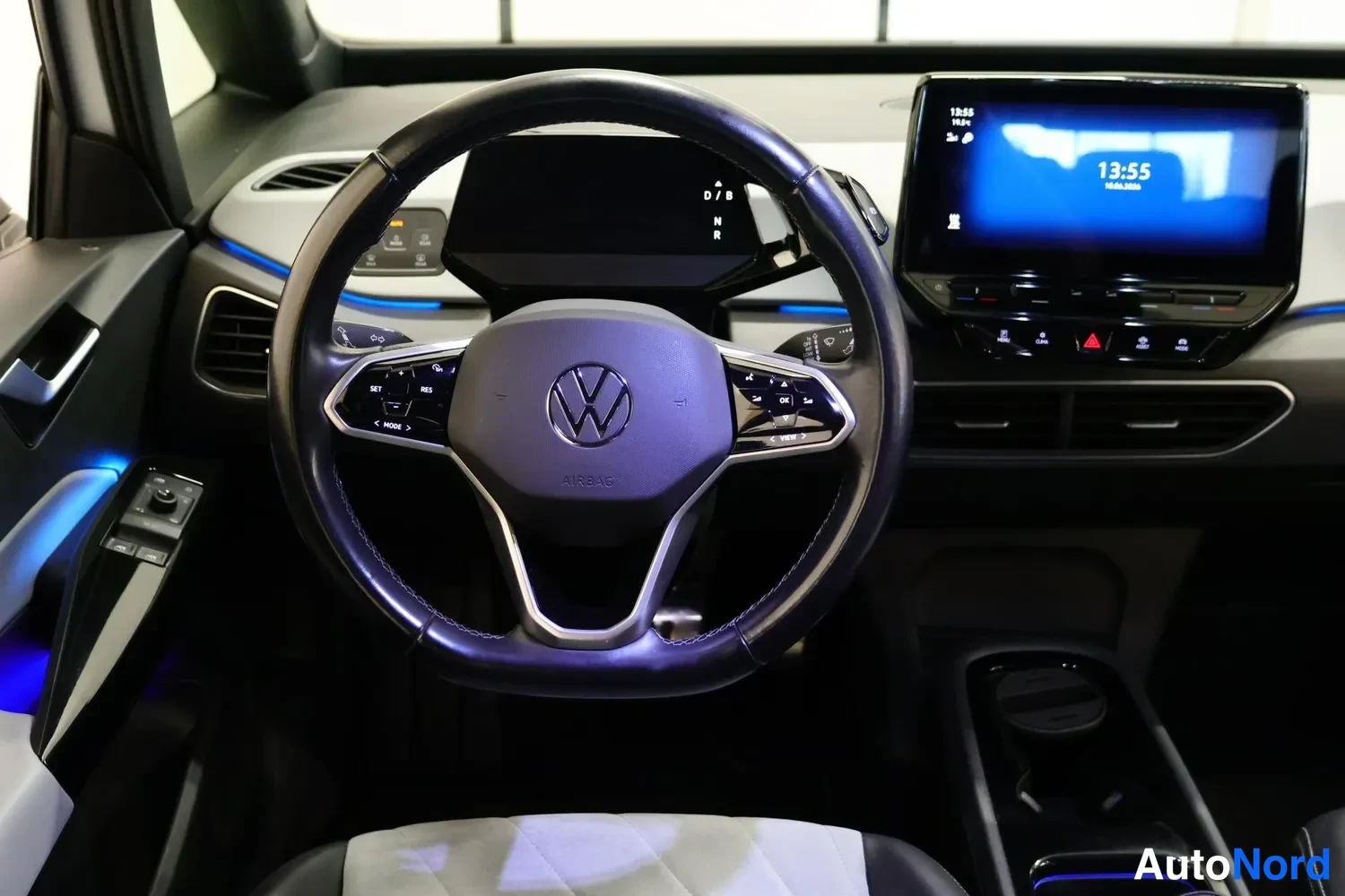 Muu: Ohjaamon etunäkymä: VW-ohjauspyörä, keskikonsolin kosketusnäyttö näyttää kelloa 13:55.