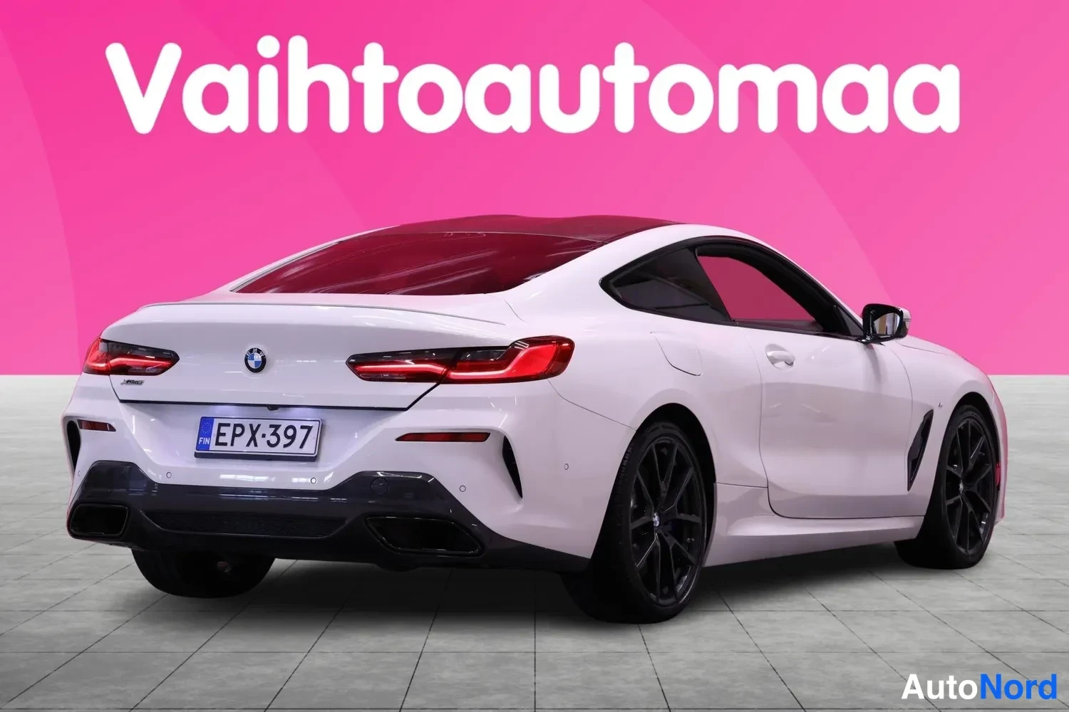 Takaviisto: Valkoinen BMW takaa ja oikeasta sivusta kuvattuna. Takavalot on päällä ja luvanumerossa. Vaaleanpunainen nallekarhu ei ole tässä kuvassa.